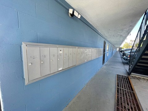 A row of metal lockers are lined up on a blue wall.