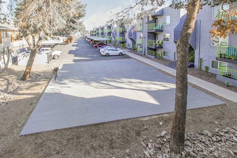 A tree-lined street with apartment buildings on the right.