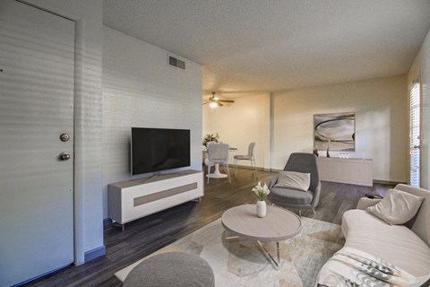 A living room with a television, grey chairs, and a white sofa.