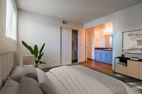 A bedroom with a large bed and a plant in a vase.
