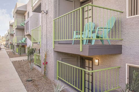 A balcony with green chairs and a green railing.