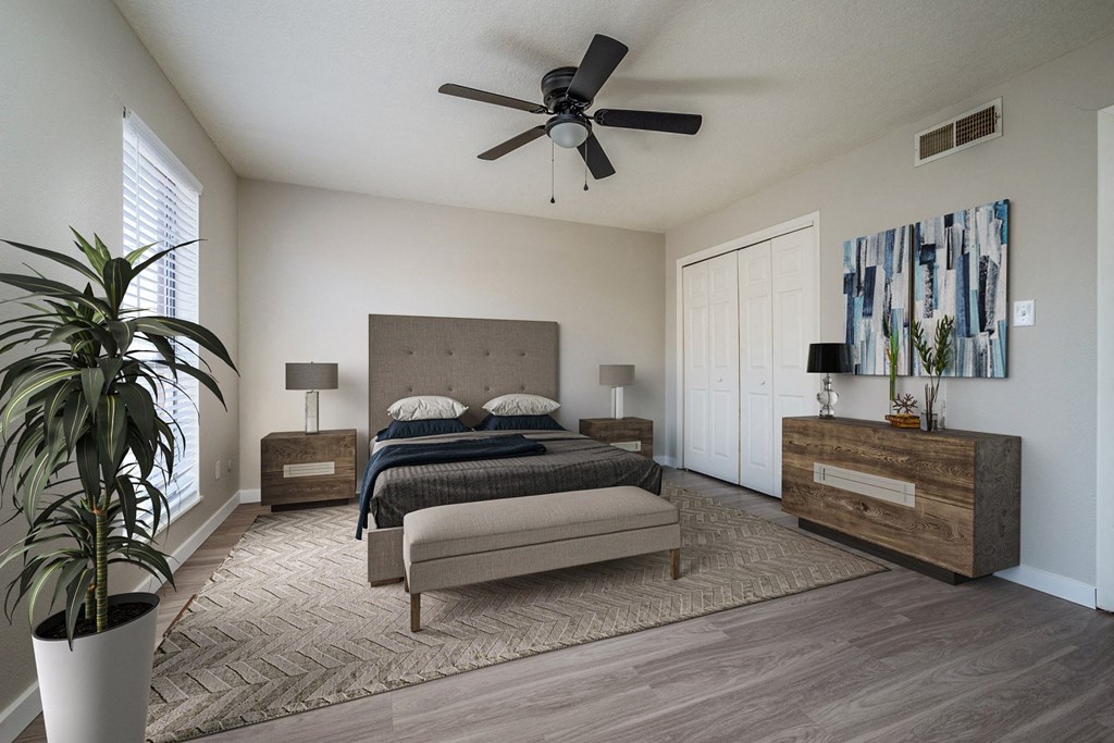 A bedroom with a large bed, a bench, and a potted plant.