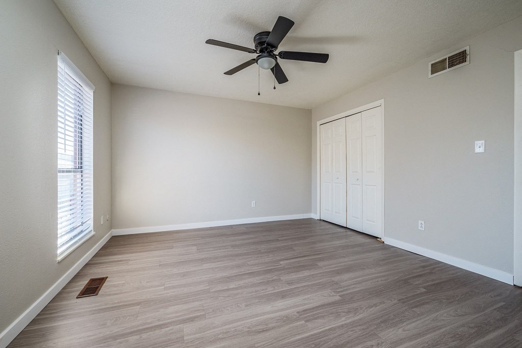 A room with a ceiling fan and wooden flooring.