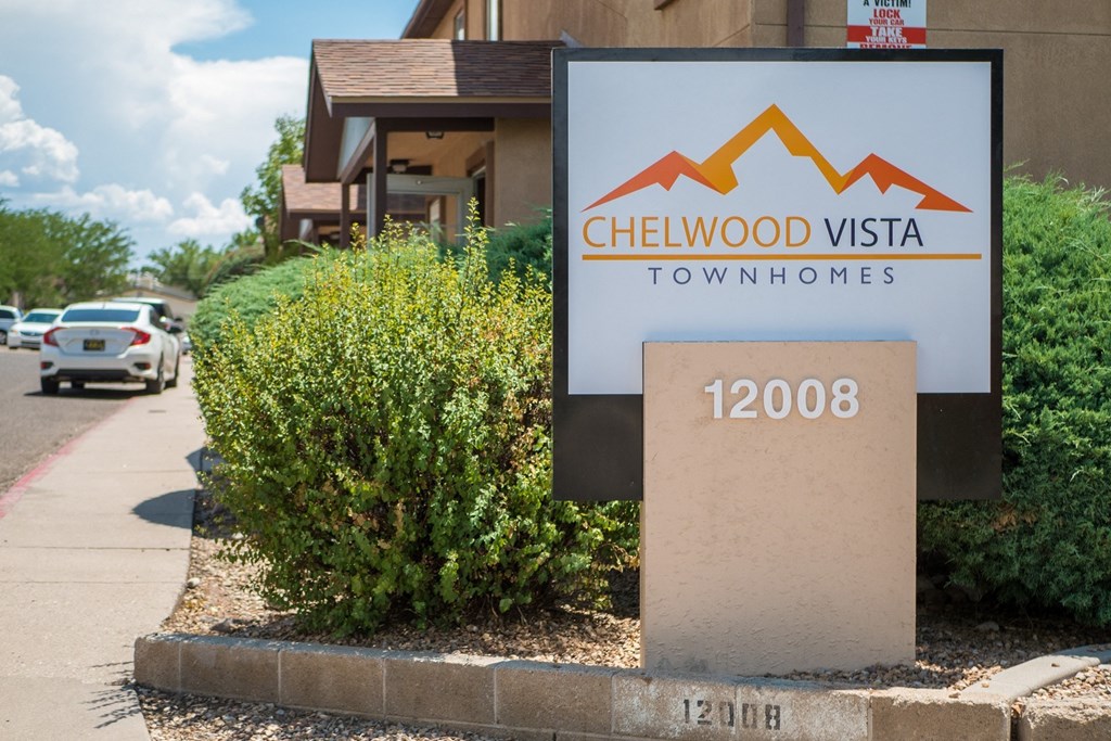 A sign for Chelwood Vista Townhomes stands in front of a building.