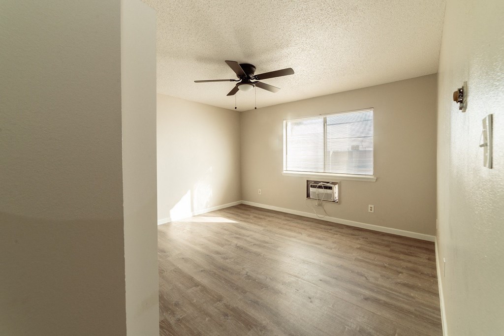 A room with a ceiling fan and a window with blinds.