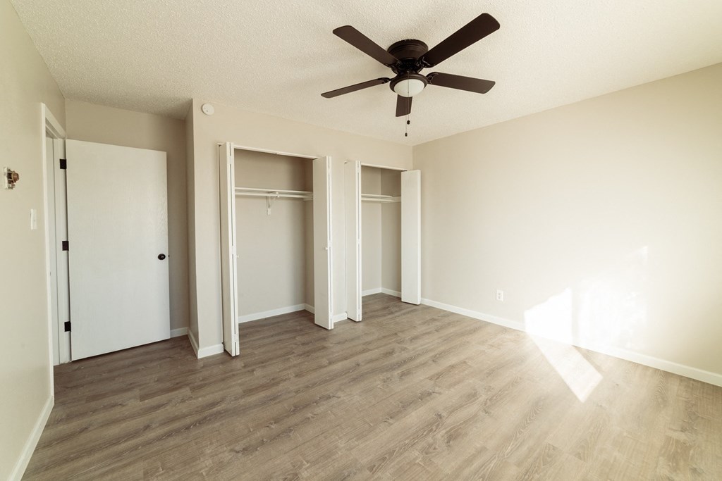 A room with a ceiling fan and light, and a door to the left.