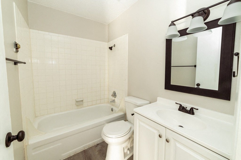 A white bathroom with a tub, toilet and sink.