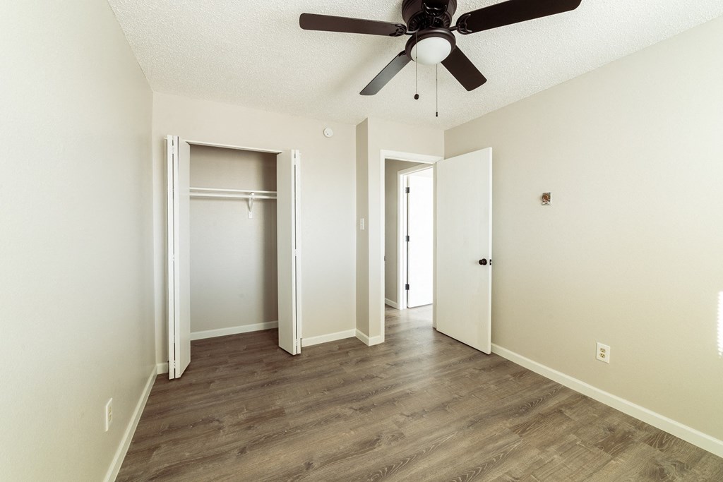 A room with a ceiling fan and wood flooring.