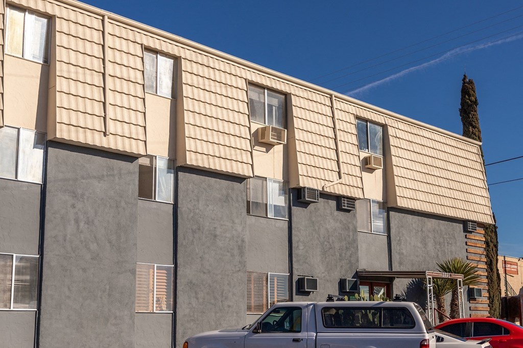 A tan building with a tan car parked in front.