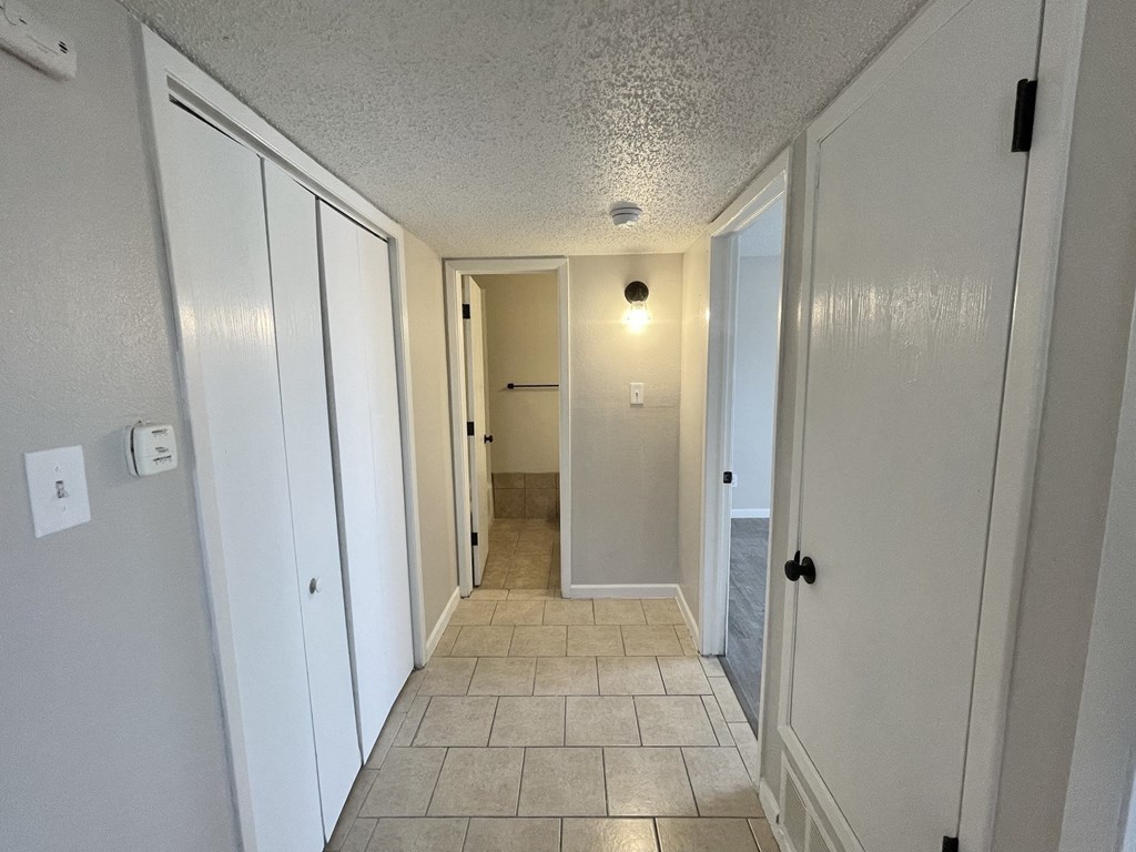 A hallway with white doors and tiled flooring.