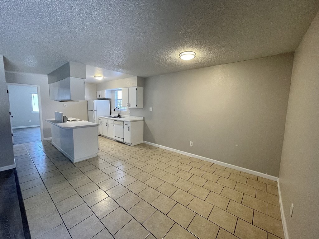 A kitchen with white cabinets and a tiled floor.