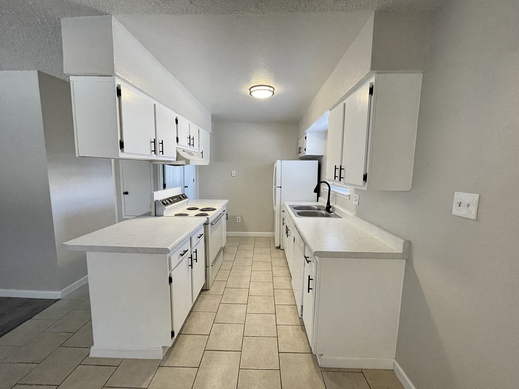 A kitchen with white cabinets and appliances.