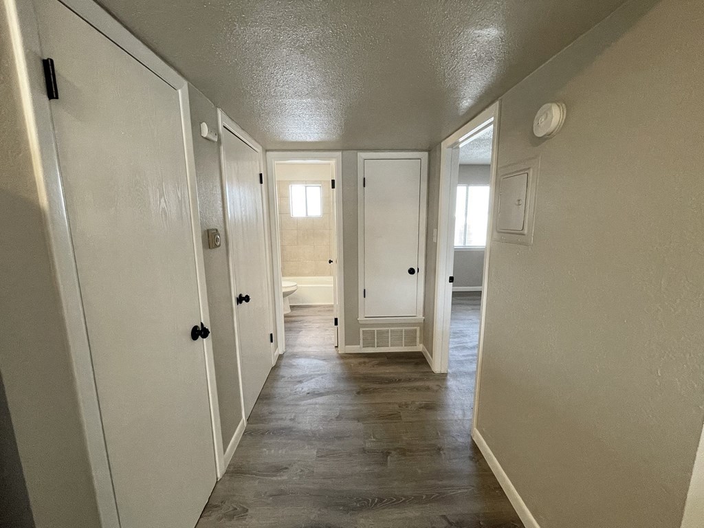 A long hallway with white doors and a tiled floor.