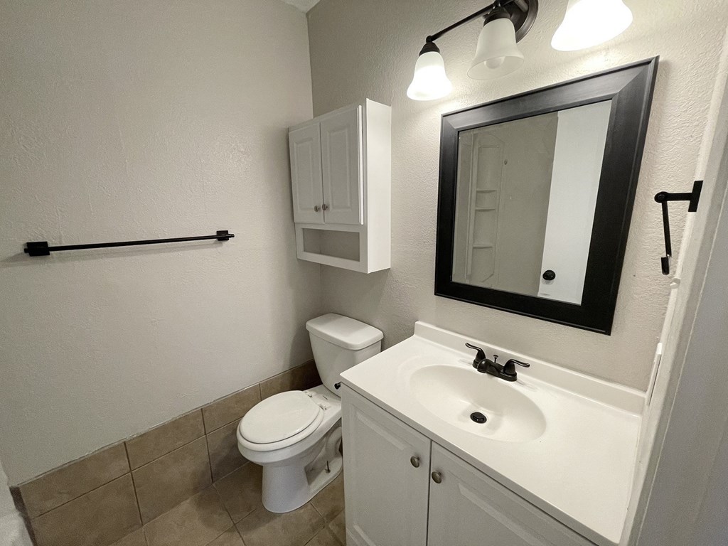 A white bathroom with a toilet, sink, and mirror.