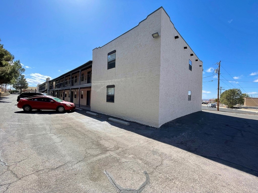 A red car is parked in front of a white building.