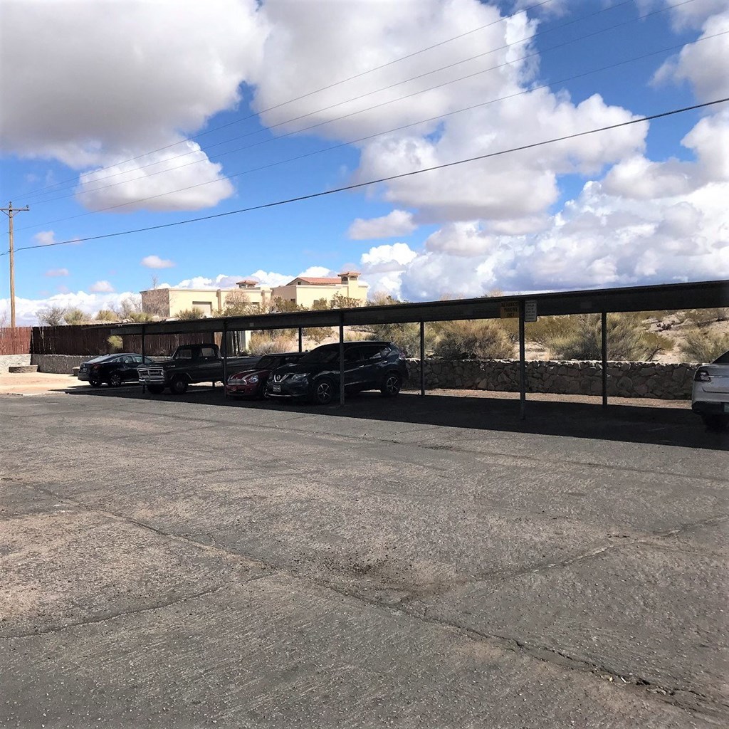 A parking lot with several cars and a building in the background.