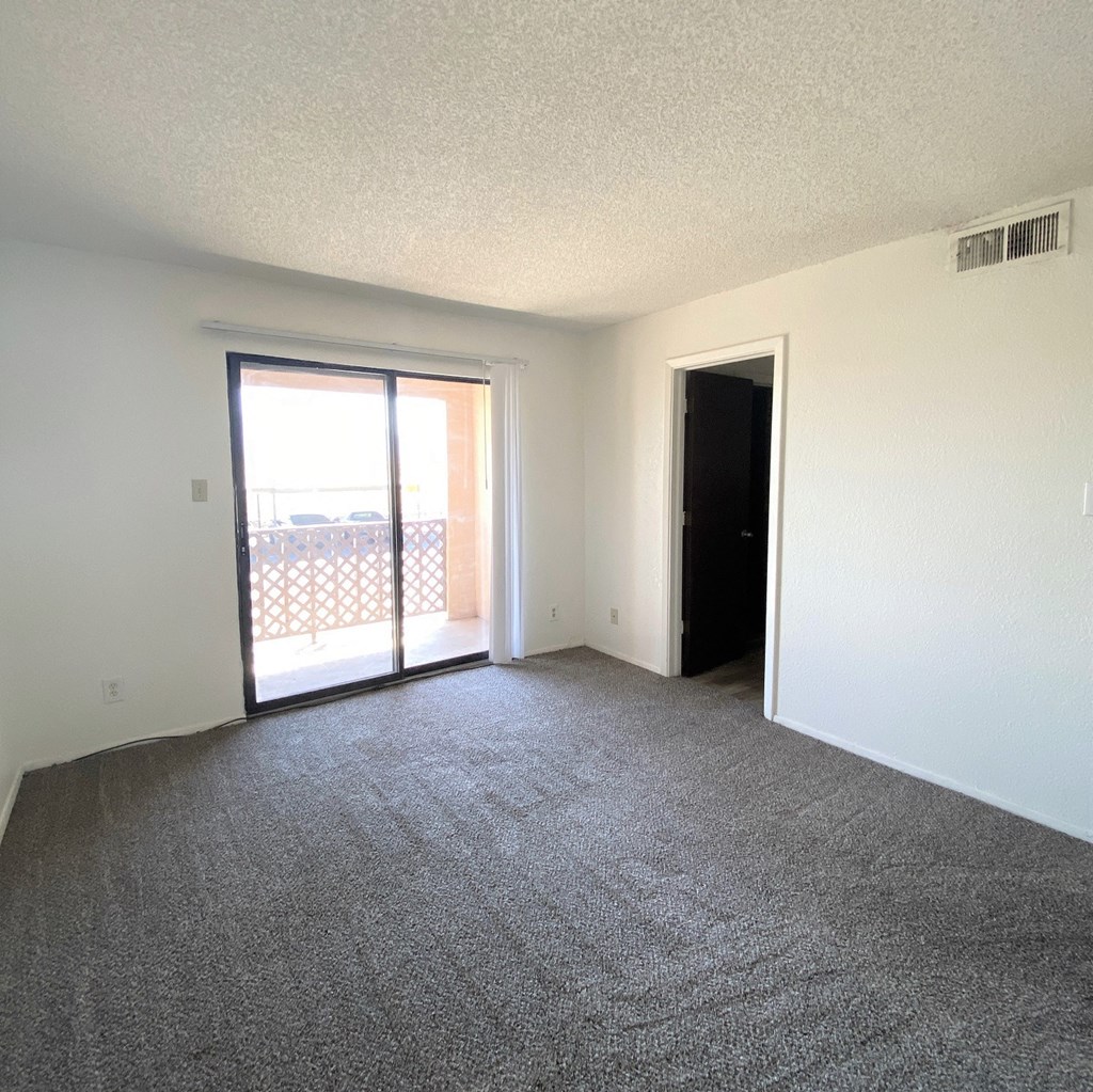 A room with a carpeted floor and a sliding glass door.