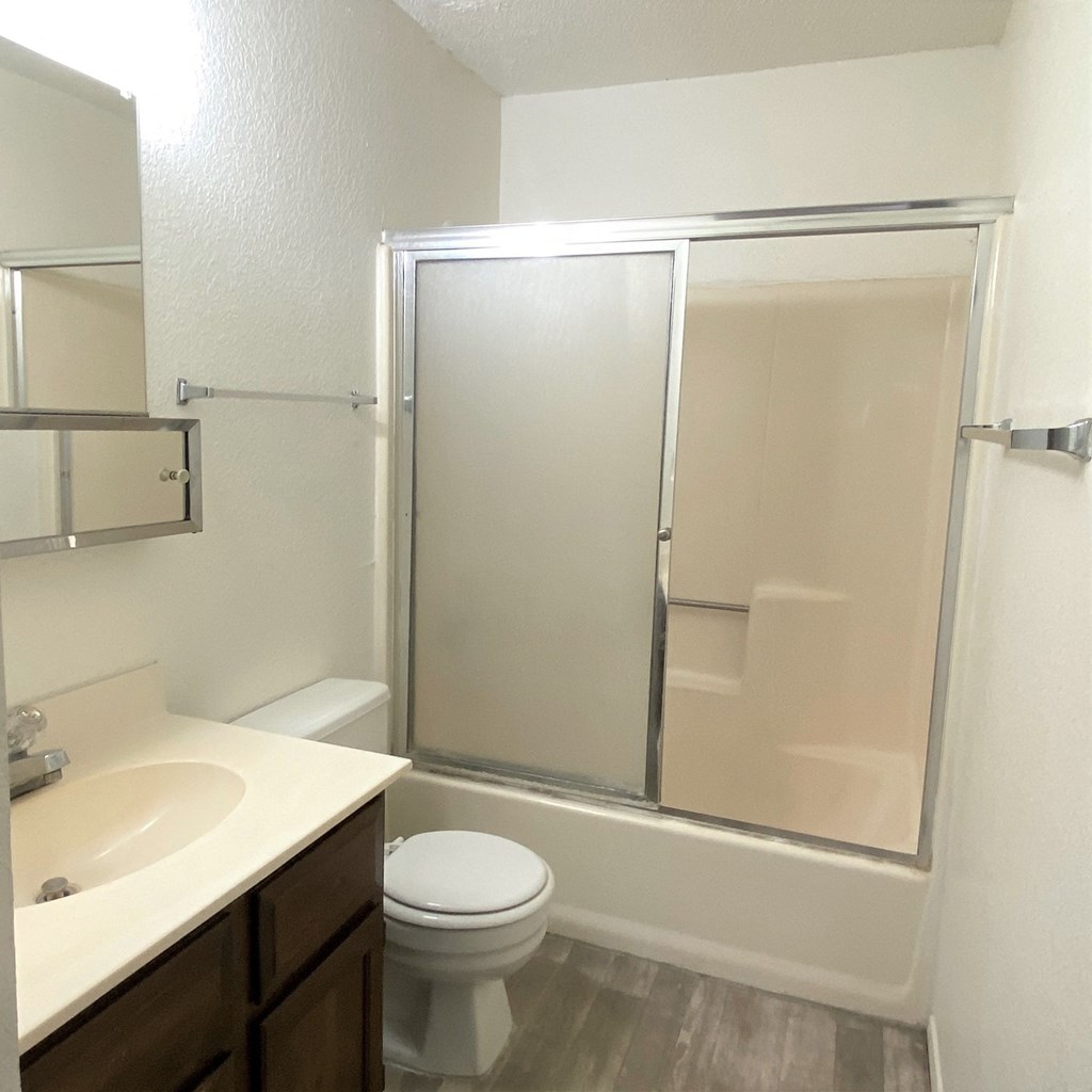 A white toilet sits in a bathroom next to a sink and a walk-in shower.