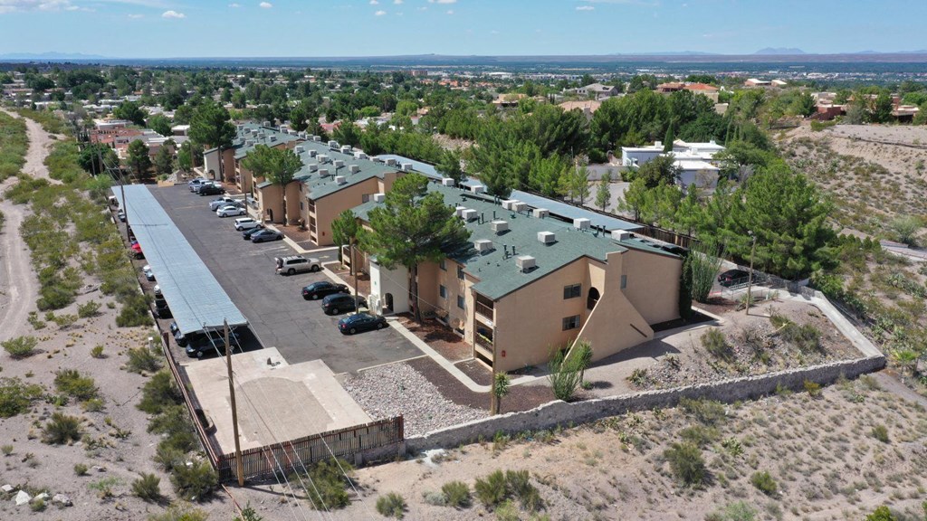 A building with a green roof is surrounded by a parking lot.