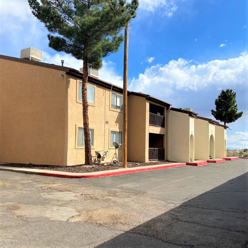 A row of apartment buildings with trees in front.