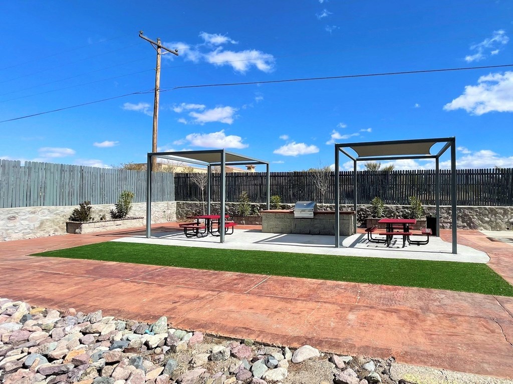 A picnic area with a table and chairs is set up in a park.