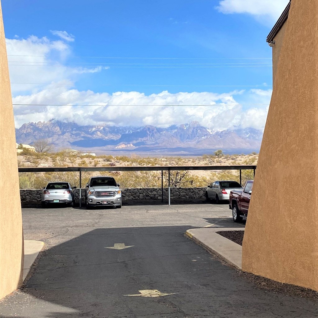A parking lot with cars and a mountain range in the background.