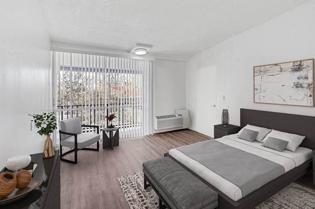 A bedroom with a large bed and a chair by a window.