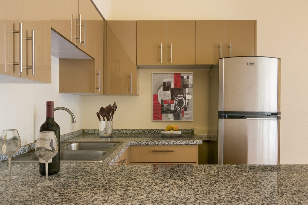 A kitchen with a granite counter top and a refrigerator.