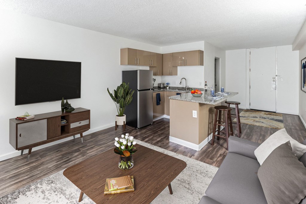 A modern living room with a flat screen TV, a wooden coffee table, and a grey sofa.