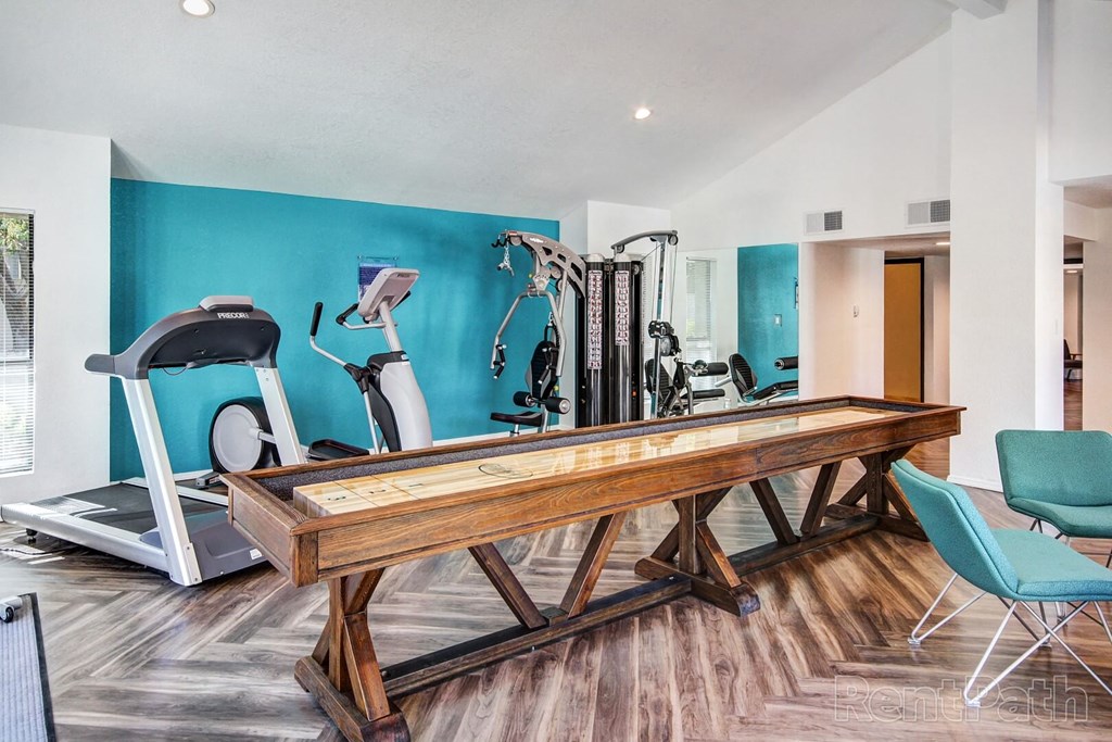 A gym with a treadmill, elliptical trainer, and other exercise equipment.