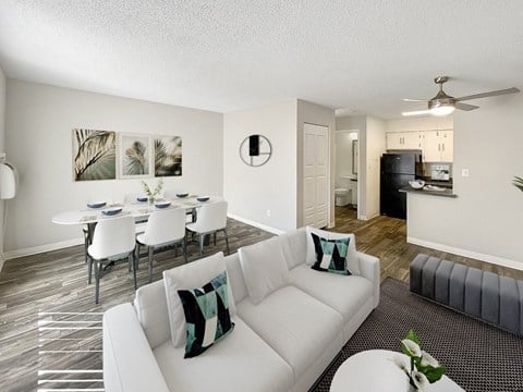 A living room with a white couch and a dining table with chairs.