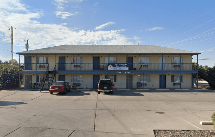 A building with a blue sign on it and two cars parked in front.