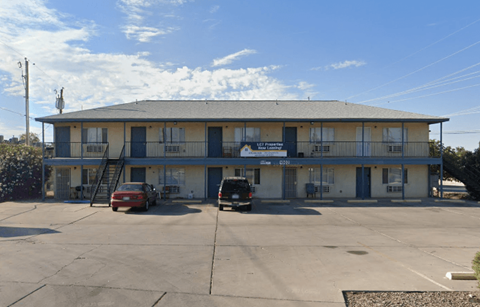 A building with a blue sign on it and two cars parked in front.