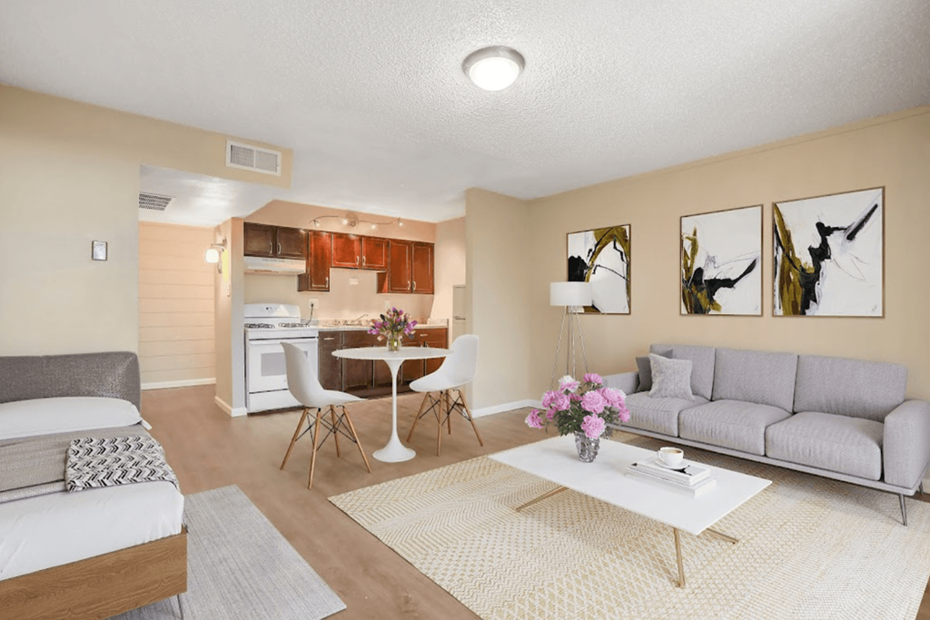 A living room with a grey couch, a white coffee table, and a dining table with chairs.