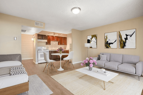 A living room with a grey couch, a white coffee table, and a dining table with chairs.