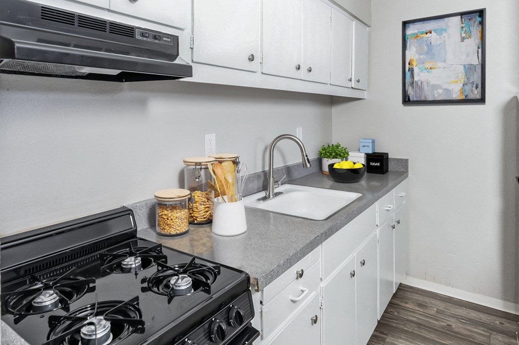 A kitchen with a black stove top and white cabinets.