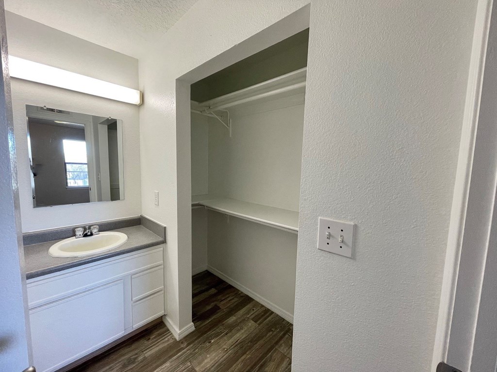 A bathroom with a sink, mirror, and wooden floors.