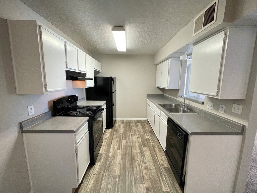 A kitchen with white cabinets and a black refrigerator.
