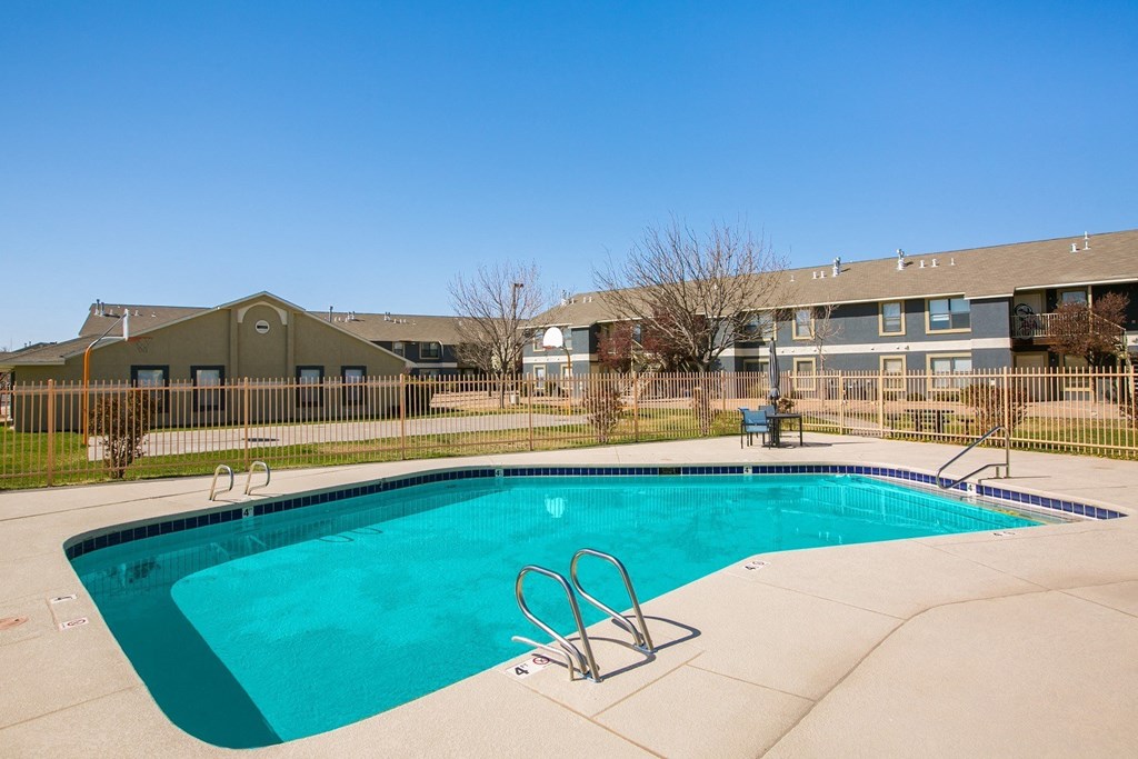 A swimming pool in front of a building with a fence around it.