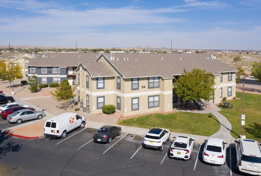 A parking lot with cars and a white van in front of a building.