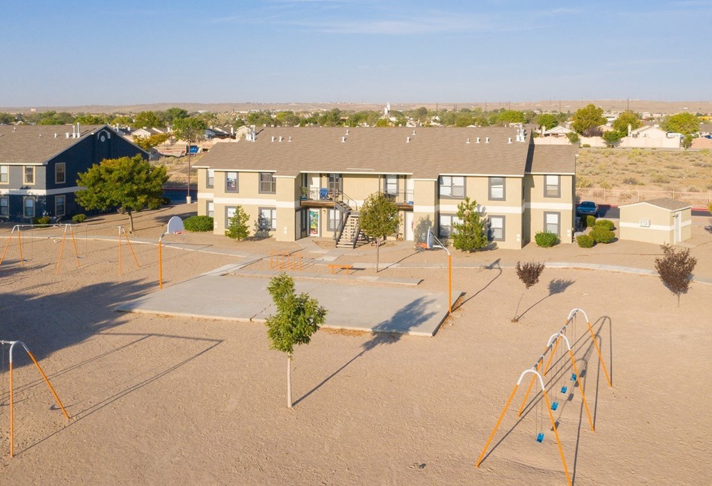 A playground with a slide and swings in front of apartment buildings.