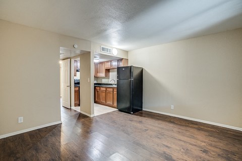 A kitchen with a black refrigerator and wooden floors.