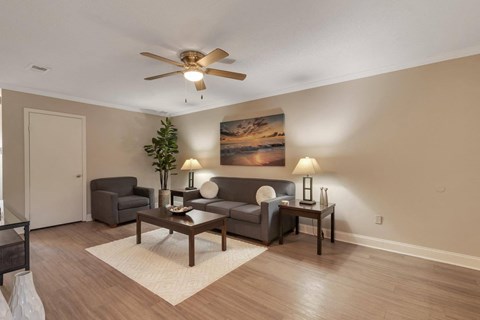 A living room with a ceiling fan, two couches, and a painting on the wall.