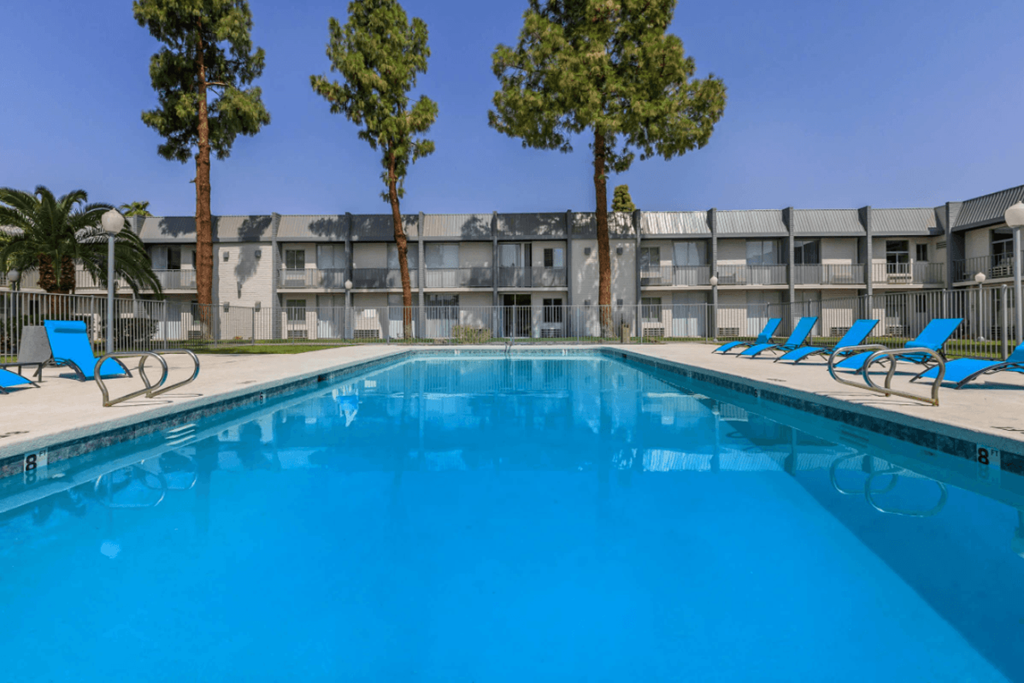 A swimming pool in front of a building with trees on the side.