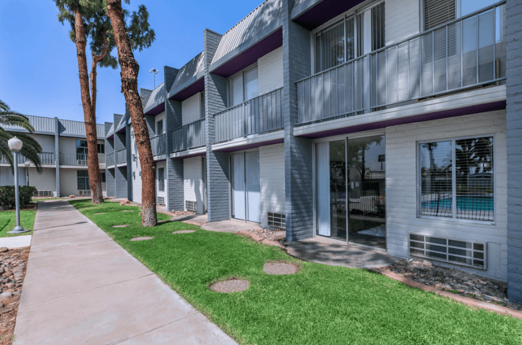 A building with a balcony and a tree in front of it.