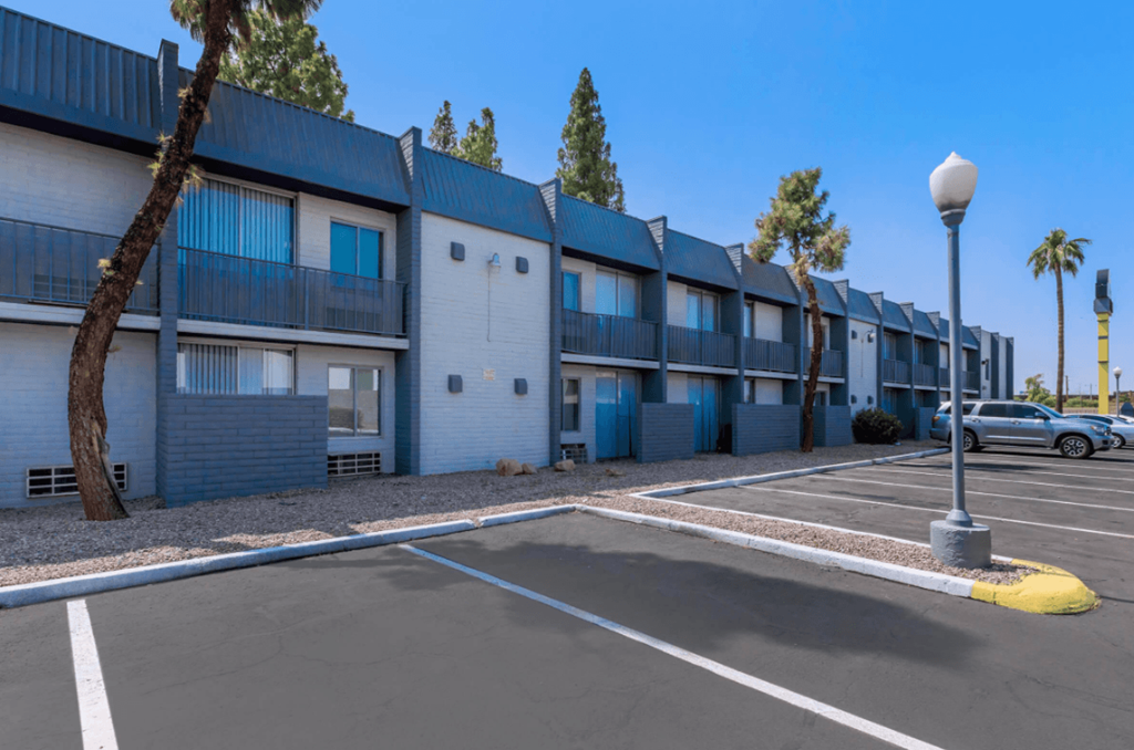 A parking lot in front of a row of apartment buildings.