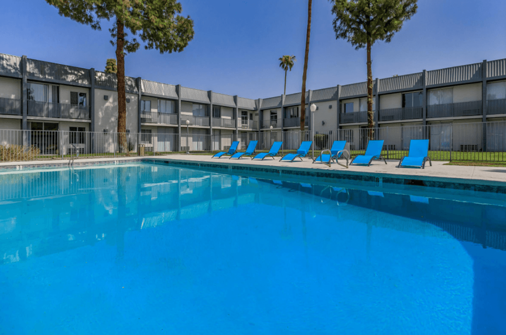 A swimming pool with blue water and lounge chairs in front of a building.