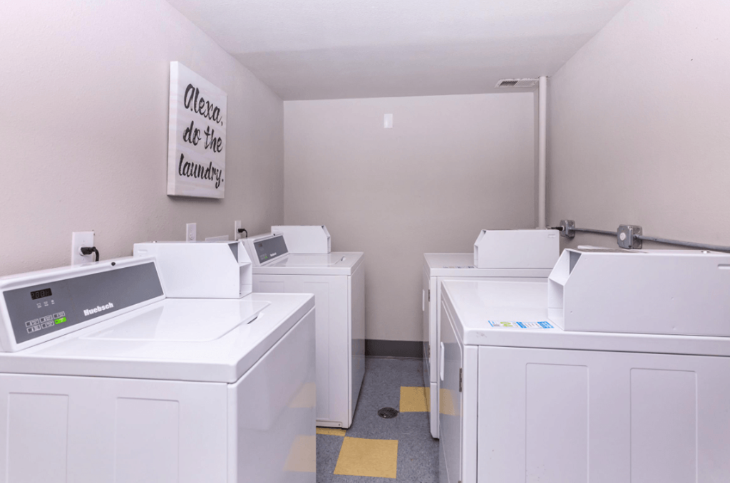 A laundry room with washers and dryers and a sign that says Alexa do the laundry.
