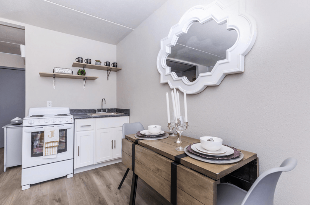 A modern kitchen with a white oven and a wooden dining table set with plates.