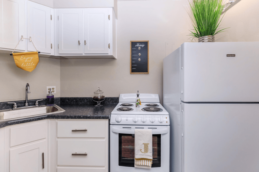 A white kitchen with a stove and a fridge.